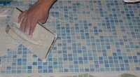 Процесс укладки мозаики в ванной